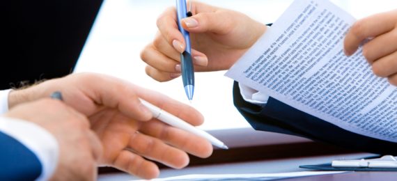 duas pessoas com canetas em mão avaliando um contrato
