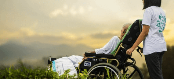 Cuidadora empurrando cadeira de rodas com idosa